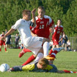 OVER THE TOP â€” Fryeburg Academyâ€™s Wyatt Andreoli (white jersey) tries to avoid a collision with the Gray-New Gloucester goalie following a shot on net during last Fridayâ€™s season opener. The Raiders blanked the Patriots 2-0. (Rivet Photo)